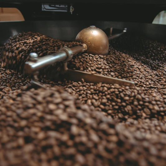 Schwarzer Espresso offen als Bohnen im Röstkessel präsentiert