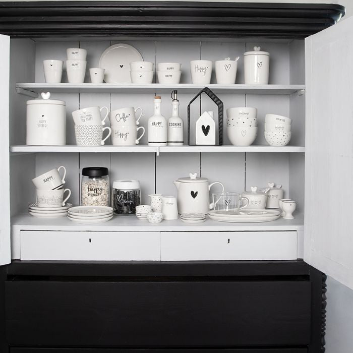 Bastion Collections Eierbecher Weiss mit schwarzem Herz dekorativ in einem Schrank platziert